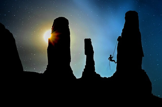 大きな山と深い谷をいくつも乗り越えて続ける人。背景には星が広がっている。